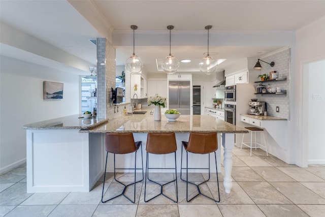 kitchen featuring white cabinets, wall chimney exhaust hood, a peninsula, stainless steel appliances, and crown molding