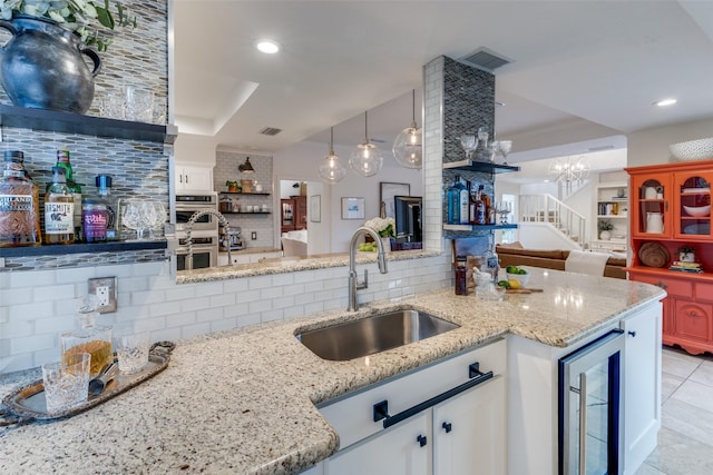 kitchen with stainless steel double oven, beverage cooler, a sink, and backsplash