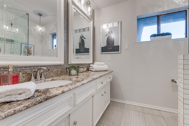 bathroom featuring a shower with door, vanity, and baseboards