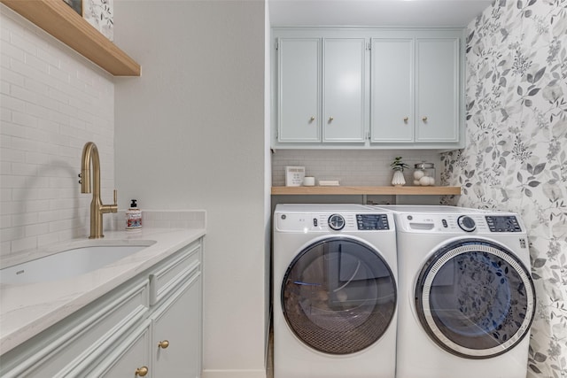 laundry room with cabinet space, washing machine and dryer, and a sink