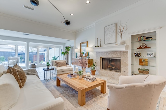 living room with visible vents, crown molding, built in shelves, a fireplace, and recessed lighting