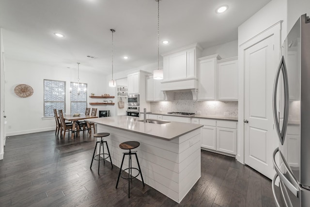 kitchen with stainless steel appliances, dark wood-style flooring, a sink, visible vents, and backsplash