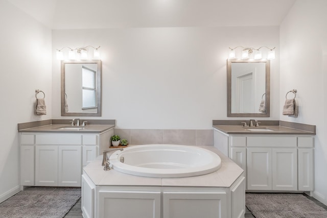 bathroom with two vanities, a sink, and a bath