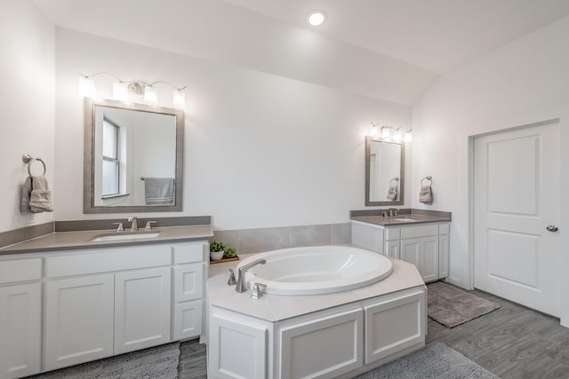 bathroom featuring lofted ceiling, two vanities, a sink, and wood finished floors