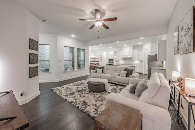 living area with recessed lighting, ceiling fan with notable chandelier, visible vents, baseboards, and dark wood finished floors