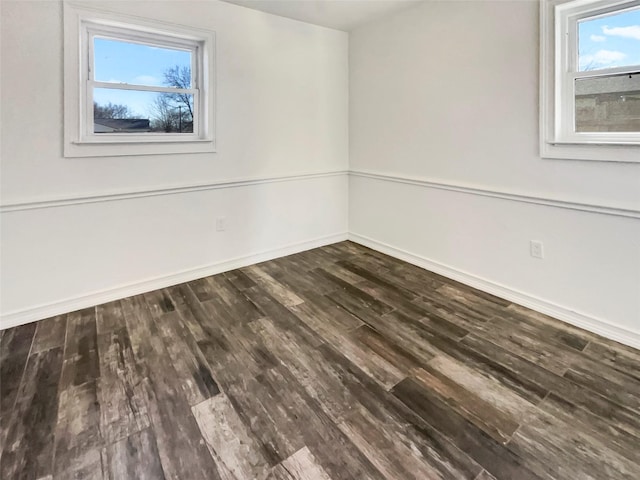 unfurnished room featuring baseboards and dark wood-type flooring