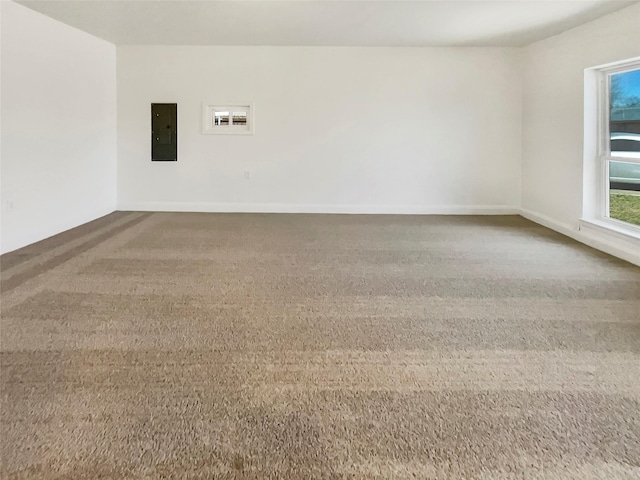 carpeted empty room featuring electric panel and baseboards