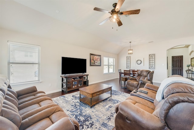 living area with lofted ceiling, ceiling fan, wood finished floors, and arched walkways