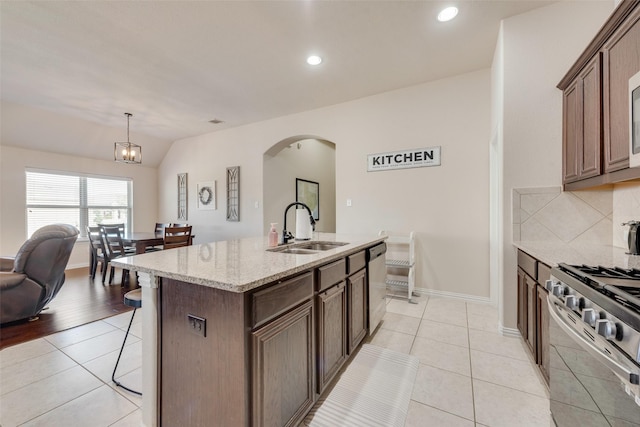 kitchen with light tile patterned floors, stainless steel appliances, a kitchen bar, and a sink