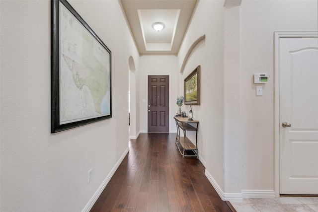 interior space with arched walkways, wood-type flooring, and baseboards