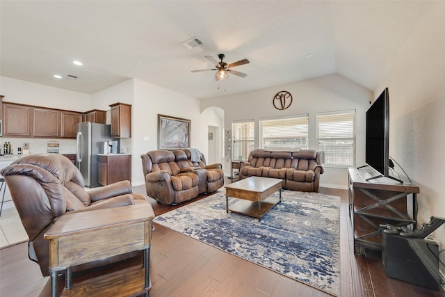 living area featuring arched walkways, visible vents, vaulted ceiling, ceiling fan, and wood finished floors