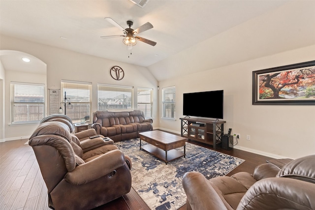 living room featuring arched walkways, dark wood finished floors, and baseboards