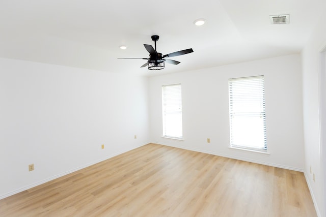 spare room featuring light wood finished floors, visible vents, and a wealth of natural light