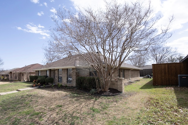 view of front facade featuring central AC, brick siding, and a front yard