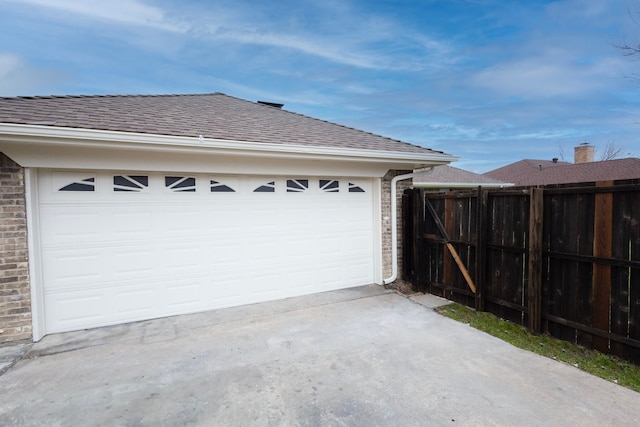 garage featuring driveway and fence