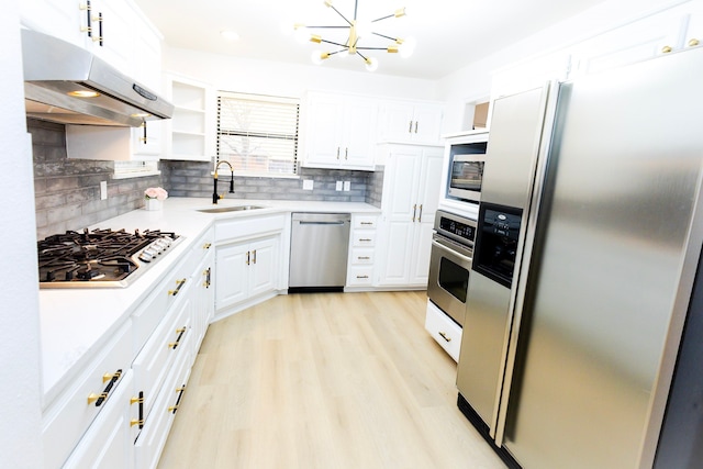 kitchen with stainless steel appliances, a sink, white cabinetry, and under cabinet range hood