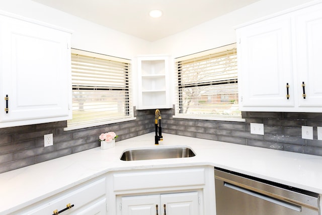 kitchen with tasteful backsplash, white cabinetry, dishwasher, and a sink