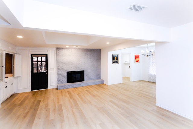 unfurnished living room with a chandelier, light wood-style flooring, recessed lighting, a fireplace, and visible vents