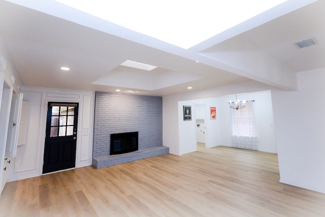 unfurnished living room with recessed lighting, a fireplace, visible vents, light wood finished floors, and an inviting chandelier