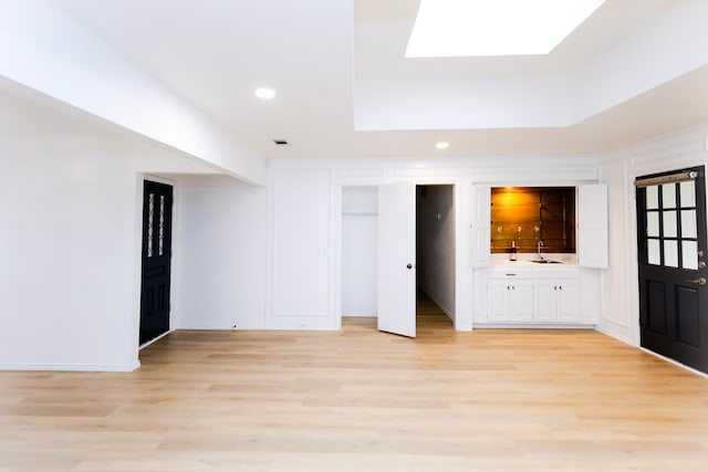 interior space featuring light wood-style floors, a skylight, a sink, and recessed lighting