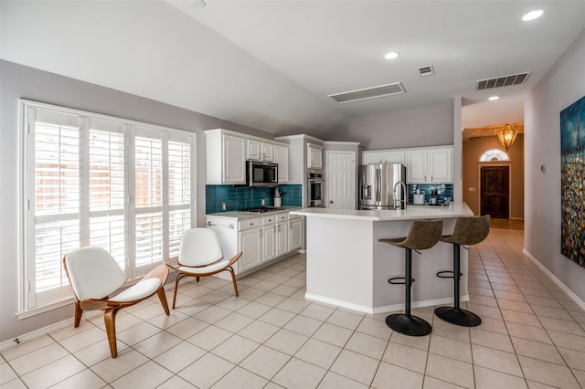 kitchen featuring light tile patterned floors, visible vents, lofted ceiling, appliances with stainless steel finishes, and light countertops