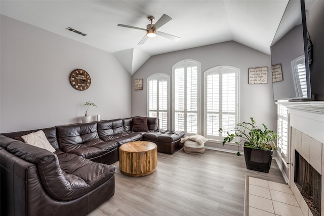 living area featuring lofted ceiling, visible vents, a ceiling fan, wood finished floors, and a tile fireplace