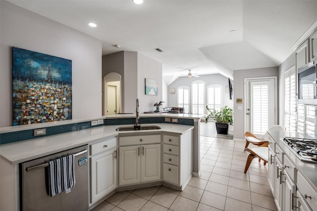 kitchen featuring appliances with stainless steel finishes, lofted ceiling, light countertops, and a sink