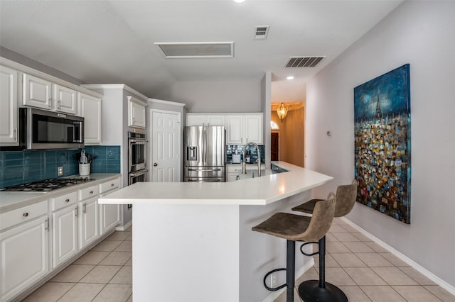 kitchen featuring a breakfast bar area, light tile patterned flooring, visible vents, appliances with stainless steel finishes, and tasteful backsplash