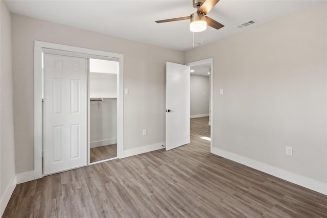 unfurnished bedroom with baseboards, a closet, visible vents, and wood finished floors