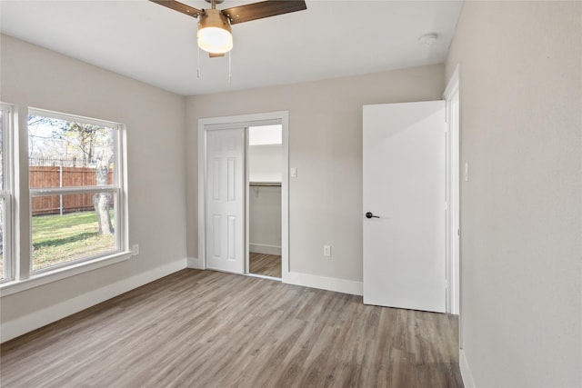 unfurnished bedroom with a closet, ceiling fan, baseboards, and wood finished floors