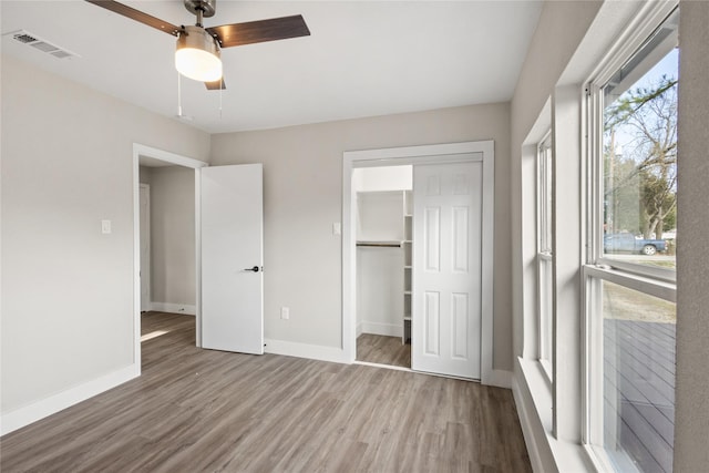 unfurnished bedroom with baseboards, visible vents, a ceiling fan, wood finished floors, and a closet