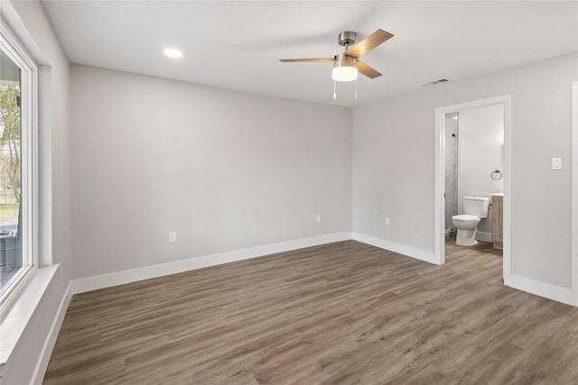 unfurnished bedroom featuring visible vents, ensuite bath, baseboards, and wood finished floors