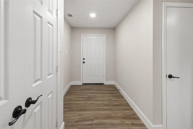 corridor featuring visible vents, baseboards, and wood finished floors