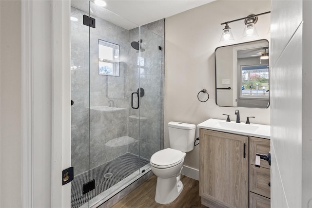 full bath featuring vanity, a shower stall, toilet, and wood finished floors