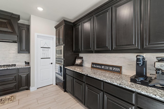 kitchen featuring light stone countertops, appliances with stainless steel finishes, and dark cabinets