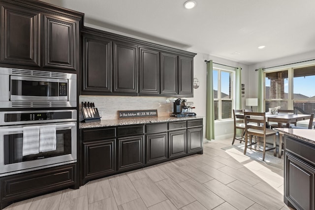 kitchen with light stone countertops, appliances with stainless steel finishes, decorative backsplash, and recessed lighting