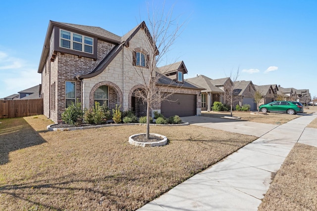 french country home featuring brick siding, fence, a garage, stone siding, and driveway