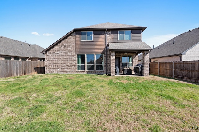 rear view of property with a patio, a fenced backyard, brick siding, a yard, and roof with shingles