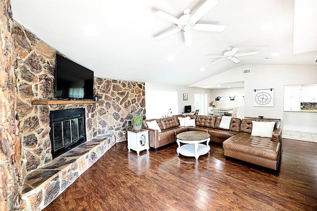 living area with lofted ceiling, a fireplace, wood finished floors, visible vents, and a ceiling fan