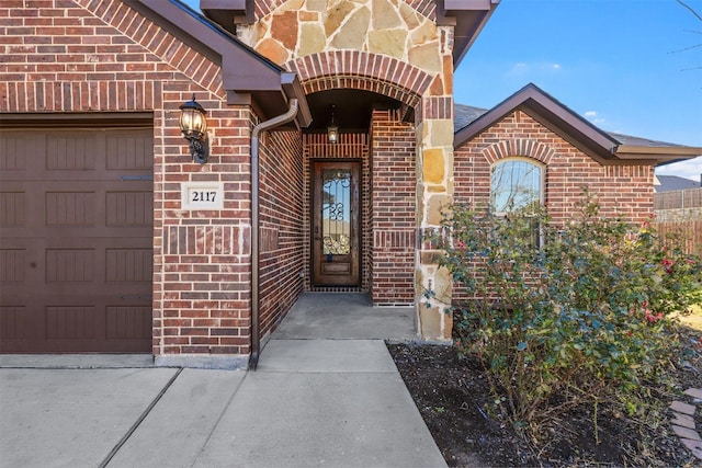 doorway to property with a garage and brick siding