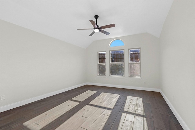 empty room with a ceiling fan, vaulted ceiling, baseboards, and wood finished floors