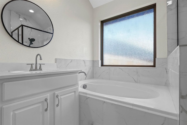 bathroom with a garden tub, a marble finish shower, a textured wall, and vanity