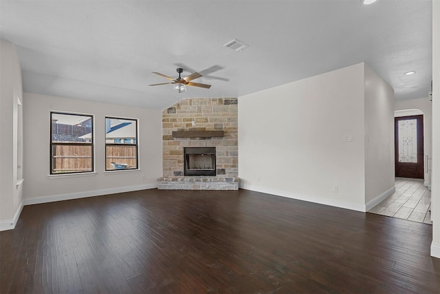 unfurnished living room featuring baseboards, visible vents, a ceiling fan, wood finished floors, and a fireplace