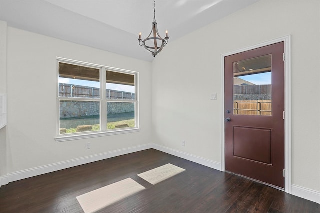 interior space featuring baseboards, a chandelier, a wealth of natural light, and wood finished floors