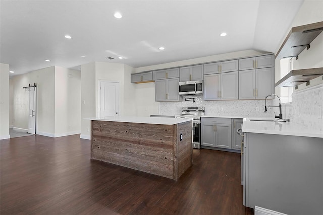 kitchen with tasteful backsplash, a kitchen island, appliances with stainless steel finishes, gray cabinets, and a sink