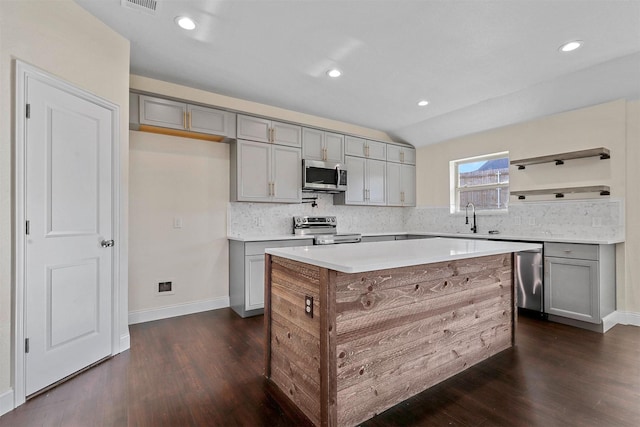 kitchen featuring dark wood-style floors, stainless steel appliances, tasteful backsplash, and gray cabinetry