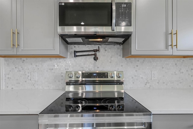 kitchen featuring stainless steel appliances, light countertops, and decorative backsplash