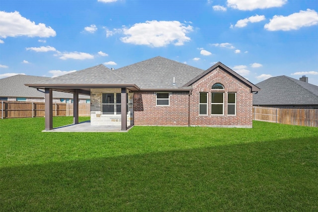 rear view of property featuring brick siding, a patio, a shingled roof, a lawn, and a fenced backyard