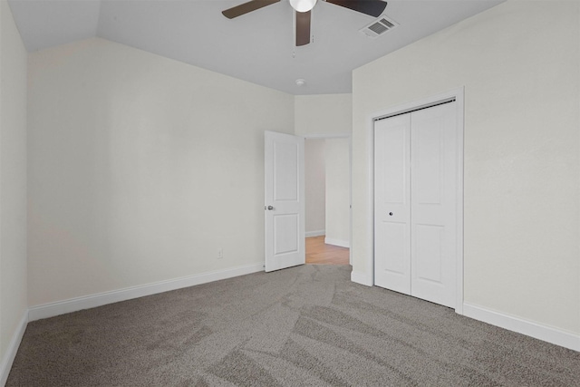 unfurnished bedroom featuring baseboards, visible vents, lofted ceiling, carpet flooring, and a closet