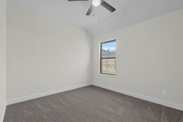 spare room featuring ceiling fan, vaulted ceiling, baseboards, and dark colored carpet